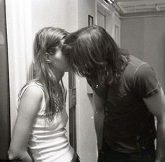 a man and woman kissing in front of a refrigerator