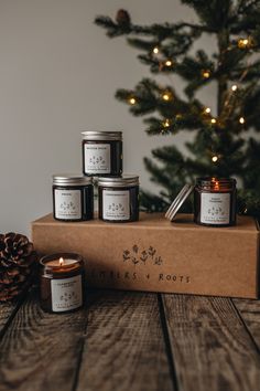 five candles sitting on top of a box next to a christmas tree and pine cones