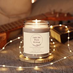 a lit candle sitting on top of a table next to a guitar and string lights