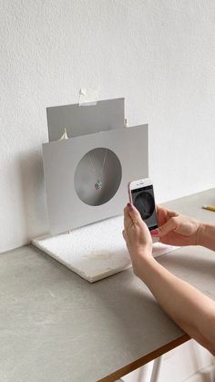 a person sitting at a table with a cell phone in front of a projector