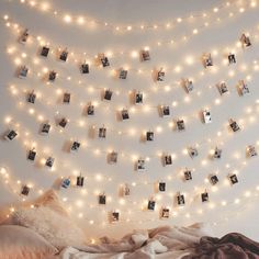 a bedroom with lights strung from the ceiling and pictures on the wall above the bed