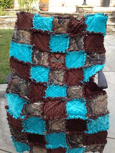 a blanket made out of old camo and blue squares is sitting on a chair