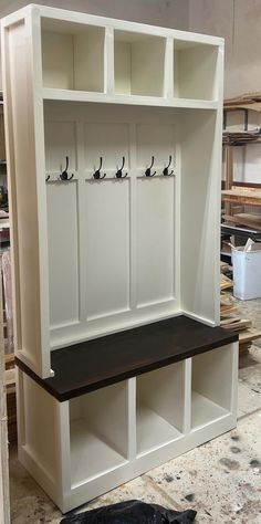 a white bench with two coats on the back and one coat rack in front of it