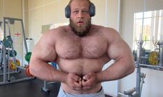 a man with headphones on his ears standing in front of a gym equipment area