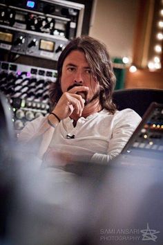 a man sitting in front of a laptop computer on top of a recording equipment desk