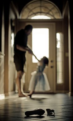 a man sweeping the floor with a mop in front of him and a pair of shoes on the ground