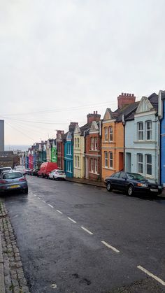 a row of colorful houses on the side of a road with cars parked in front