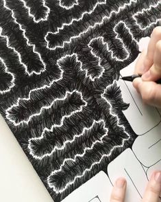 someone is drawing an intricate pattern on a piece of paper with black marker and pen