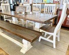 a wooden table with two white chairs next to it and a bench on the floor