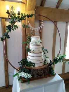 a white wedding cake with greenery and bunting around it on top of a table