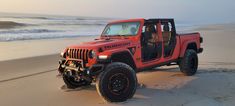 an orange jeep is parked on the beach