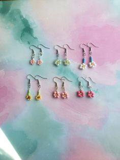 six pairs of earrings on top of a colorful background with watercolor paint in the background