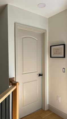 an empty hallway with a white door and wooden stairs in front of the entrance way