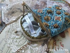 a blue purse sitting on top of a table covered in lace and brooches