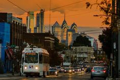 a city street filled with lots of traffic and tall buildings in the background at sunset