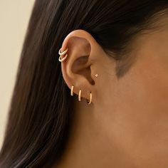 a woman wearing gold ear cuffs with two small bars on the back of her ear