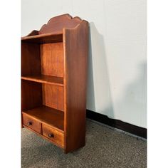 a wooden book shelf with drawers next to a wall