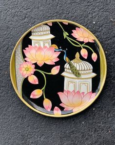 a decorative plate with flowers and a bird on it's side, sitting on the ground