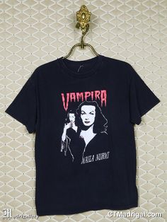 "(BIG NEWS➔ \"SHIRT\" is my newest vintage horror & band tee store, it's at my personal site: www.CTMadrigal.com, via the \"SHIRT\" link in the site's menu. You can join the mailing list for new arrivals too.) VAMPIRA t-shirt. Vintage and rare, soft, faded black, short sleeve T-shirt. Male or Unisex style. If there is no photo posted of the back of the T-shirt it means the back is unprinted. The size, if shown on label, may not represent modern sizing, please go by measurements to ensure best fi Horror Graphic Print Top For Alternative Fashion, Vintage Black Top For Fan Conventions, Vintage Black Tops For Fan Conventions, Black Vintage Tops For Fan Conventions, Vintage Halloween Concert T-shirt, Vintage Halloween Fan Merchandise T-shirt, Black Deadstock T-shirt For Halloween, Black Horror Tops For Alternative Fashion, Vintage Black Top For Costume Party