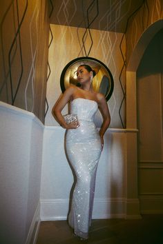 a woman standing in front of a mirror wearing a white sequin dress and holding her hands on her hips