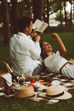 a man and woman are laying on the grass with books in their hands as they look at each other