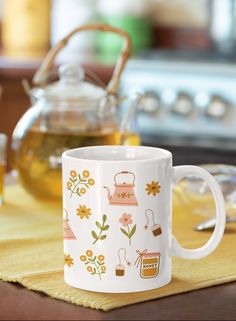 a white coffee mug sitting on top of a wooden table next to a tea pot