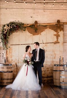 a bride and groom standing next to each other in front of barrels with candles on them