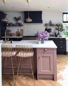 a kitchen with two bar stools next to an island in the middle of it