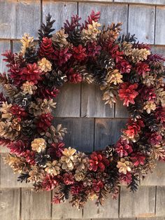 a wreath is hanging on the side of a wooden wall with red and green leaves