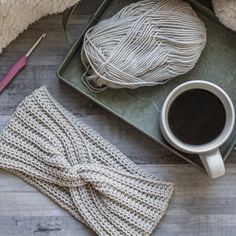 a cup of coffee and some yarn on a tray