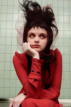 a woman with freckled hair sitting on the ground in front of a tiled wall