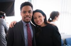 a man and woman are posing for a photo in front of a window at an event