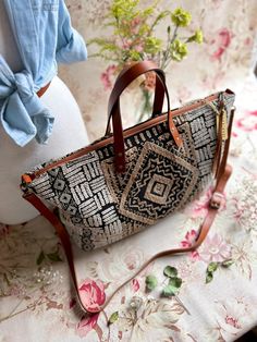 a handbag sitting on top of a table next to a vase with flowers in it