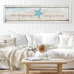 a living room filled with white furniture and pillows on top of a wooden coffee table