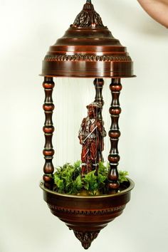 a musical instrument with a statue in the middle and greenery on it's sides