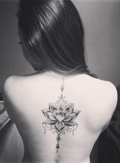 a woman's back with a lotus tattoo on her left side ribcage