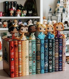 a row of disney princess figurines sitting on top of each other in front of books