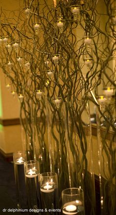 vases with candles and branches in them are lined up on a table next to each other