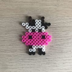 a sheep made out of legos sitting on top of a wooden table with white and pink circles