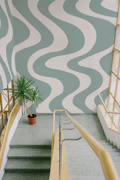 the stairs are next to a potted plant in front of a wall with wavy waves painted on it