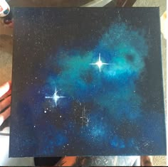 someone is holding up a painting with stars on it