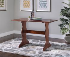 a wooden table sitting on top of a rug next to a potted green plant