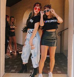 two young women standing next to each other in front of a building with sunglasses on