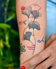 a woman's arm with tattoos on it and flowers in the middle of her arm