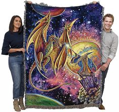 a man and woman holding up a large tapestry with two dragon on it's back