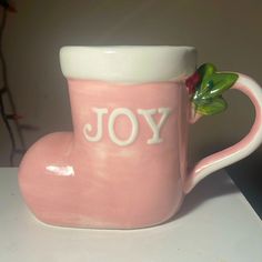 a pink coffee cup with the word joy painted on it and a strawberry sticking out of it