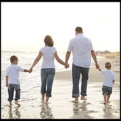 a family walking on the beach holding hands