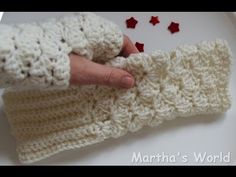 a hand is holding onto a white crocheted mitt with red stars on it