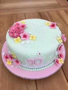 a birthday cake decorated with flowers and the number 80 on it is sitting on a wooden table