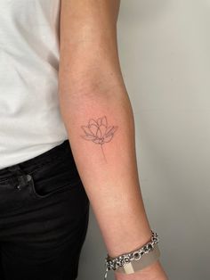 a woman's arm with a small flower tattoo on the left side of her arm